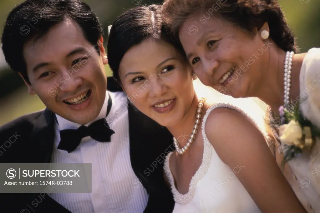 Close-up of a newlywed couple smiling with a mature woman