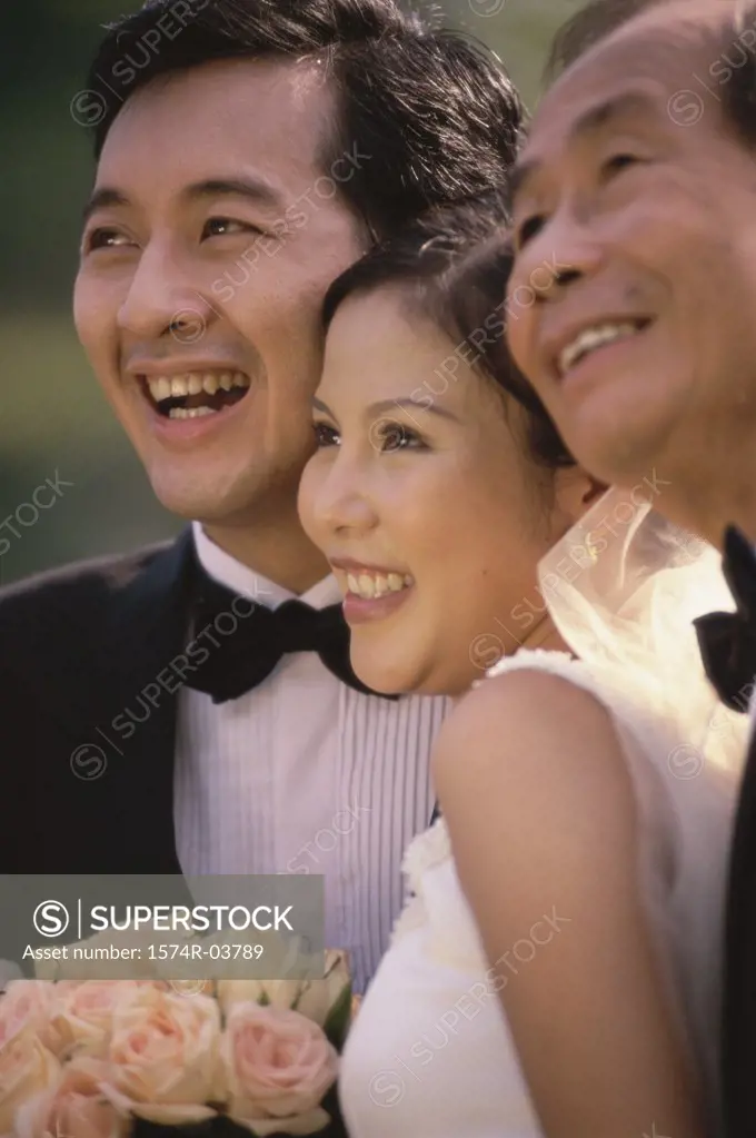 Close-up of a newlywed couple smiling with a mature man