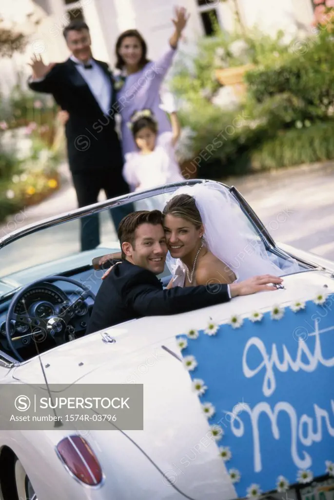 Portrait of a bride and her groom sitting in a convertible car