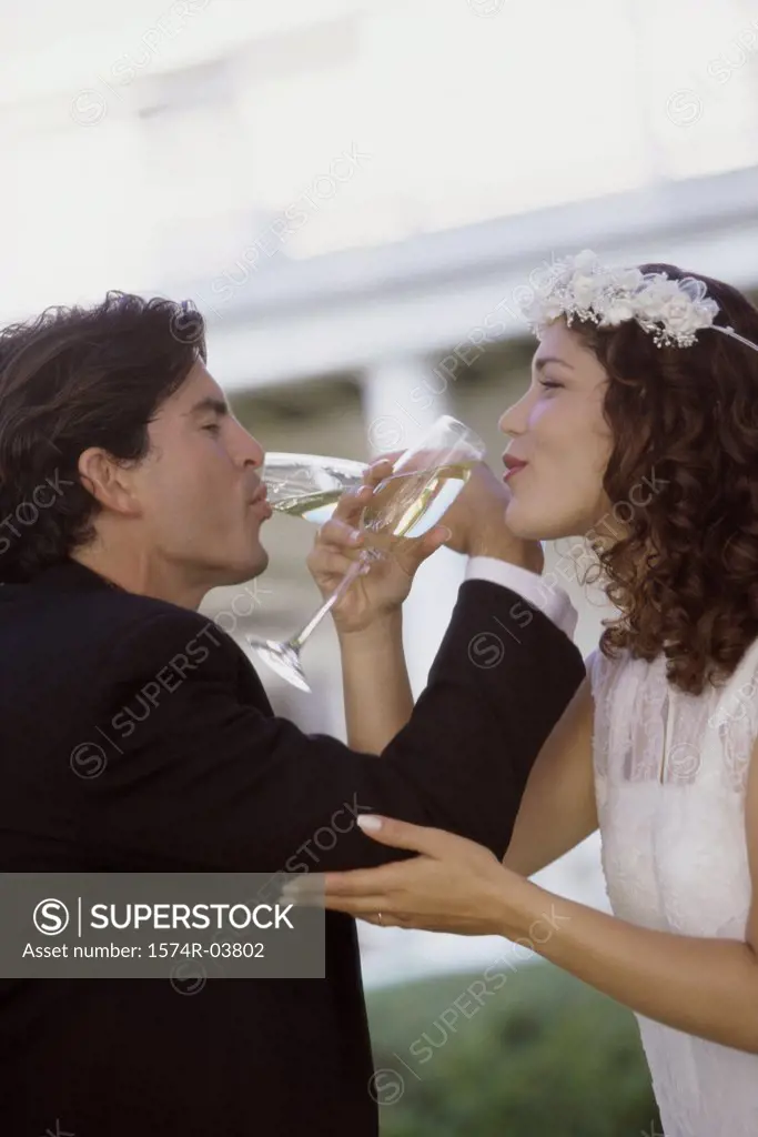 Side profile of a newlywed couple drinking champagne