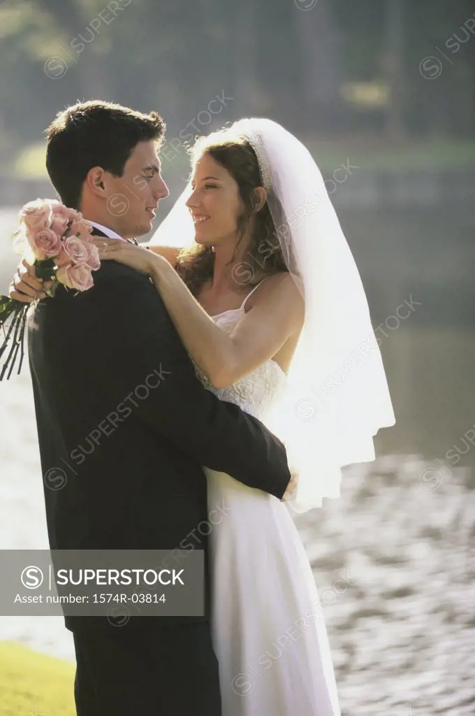 Newlywed couple embracing near a lake