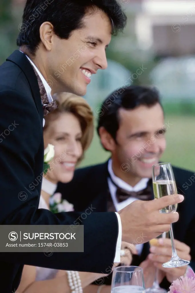 Newlywed young man toasting champagne with mid adult couple
