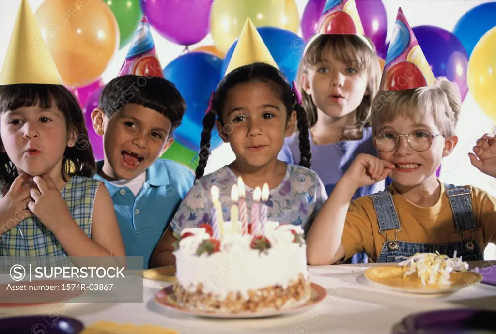 Group of children in front of a birthday cake at a birthday party