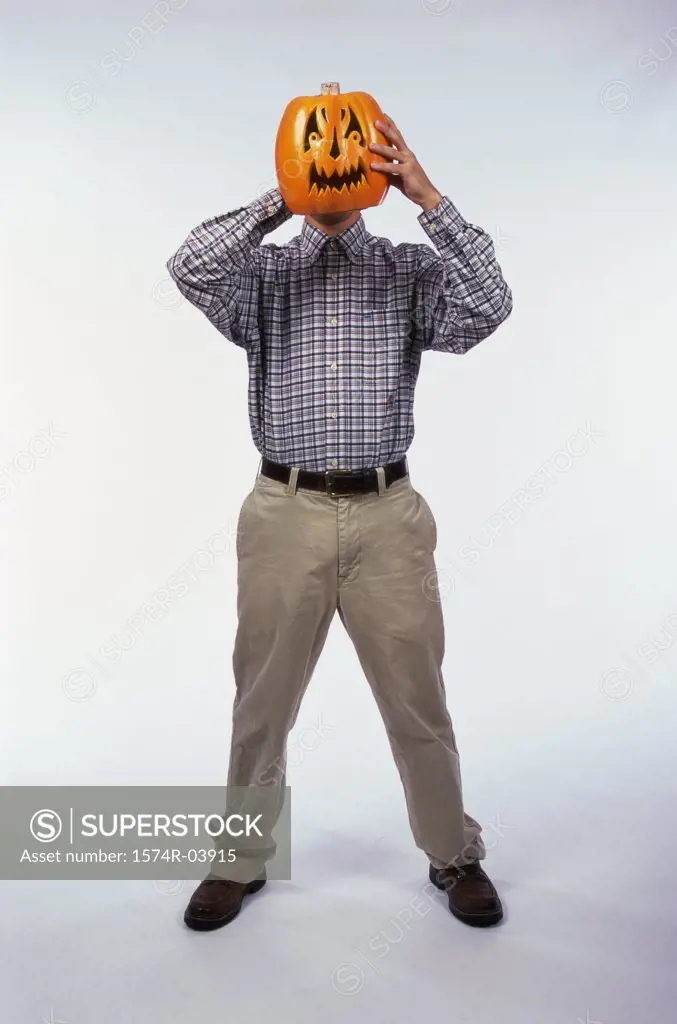 Man holding a carved Halloween pumpkin in front of his face