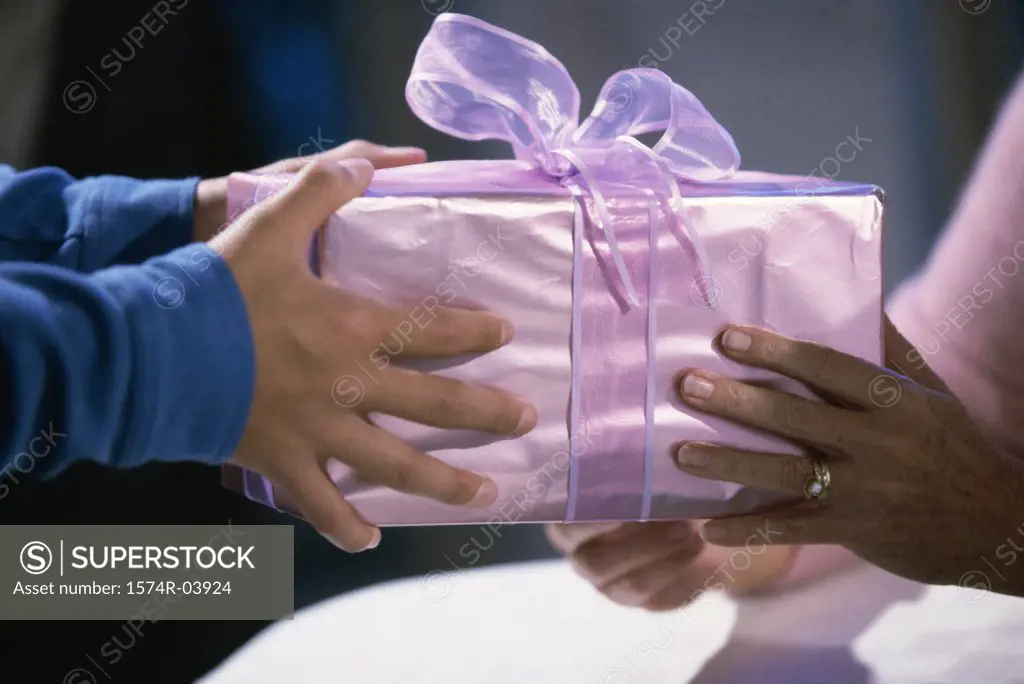 Two people holding a wrapped gift