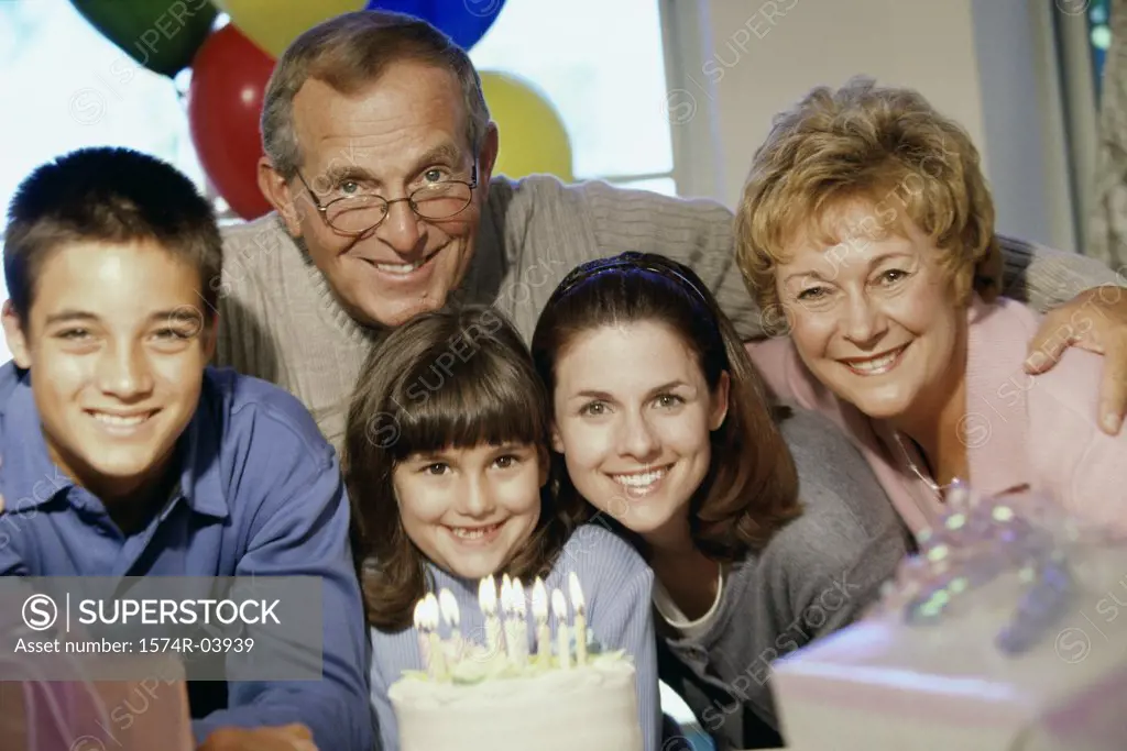 Portrait of grandparents and their grandchildren in front of a cake