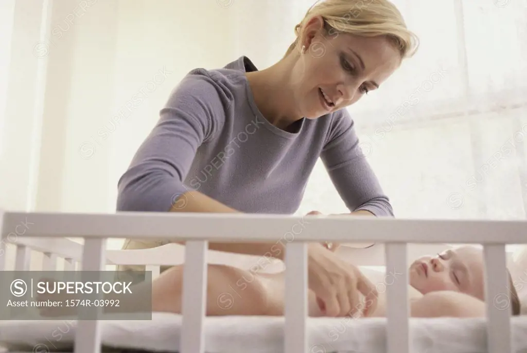 Mother looking at her baby boy in a crib