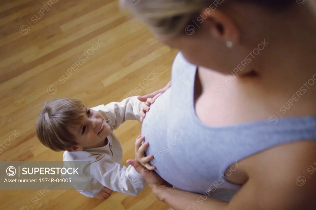 High angle view of a son touching his pregnant mother's abdomen