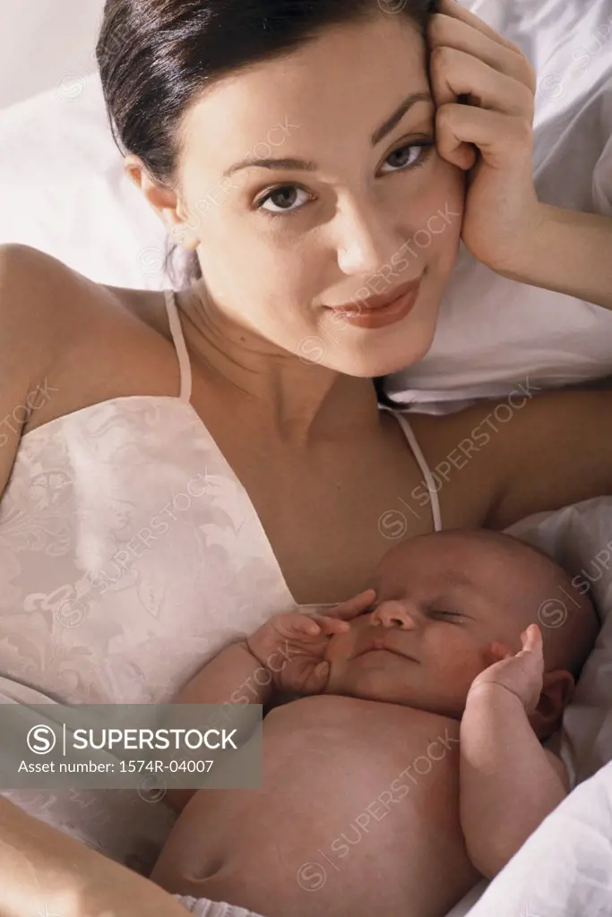Portrait of a mother lying on a bed with her baby boy