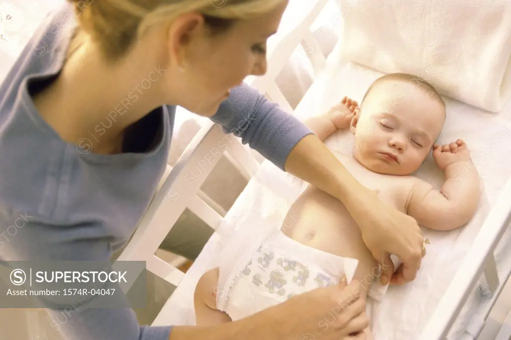 High angle view of a mother changing diaper of sleeping baby boy