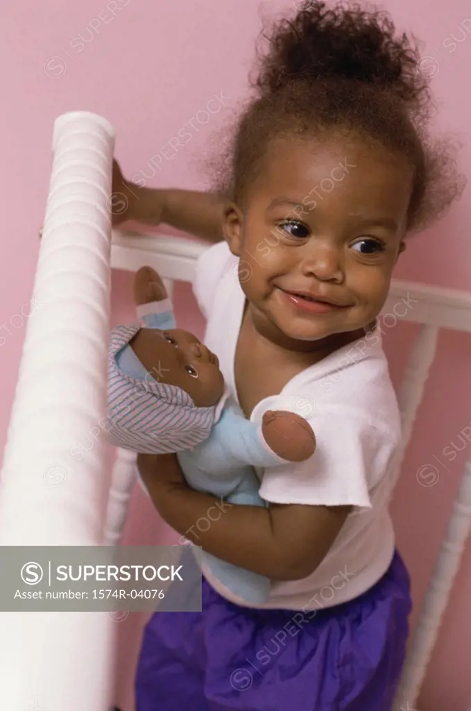 High angle view of a baby girl holding a doll