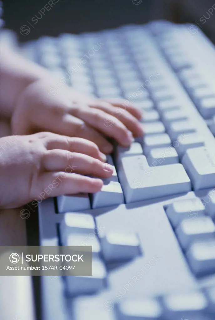 Close-up of a baby's hands on a computer keyboard