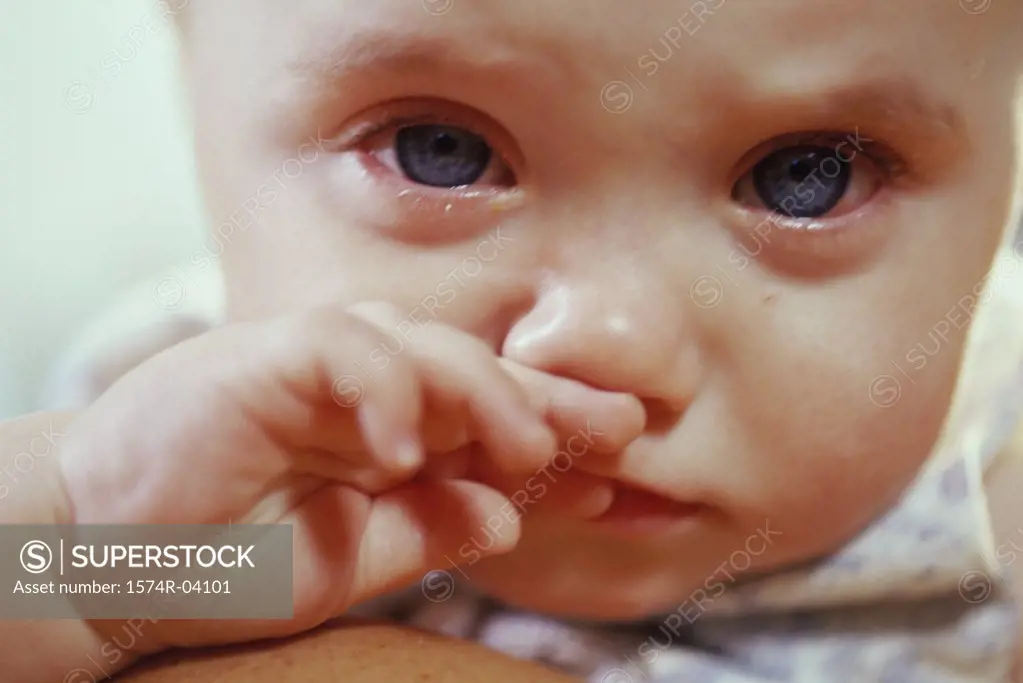 Close-up of a baby boy crying and rubbing his nose