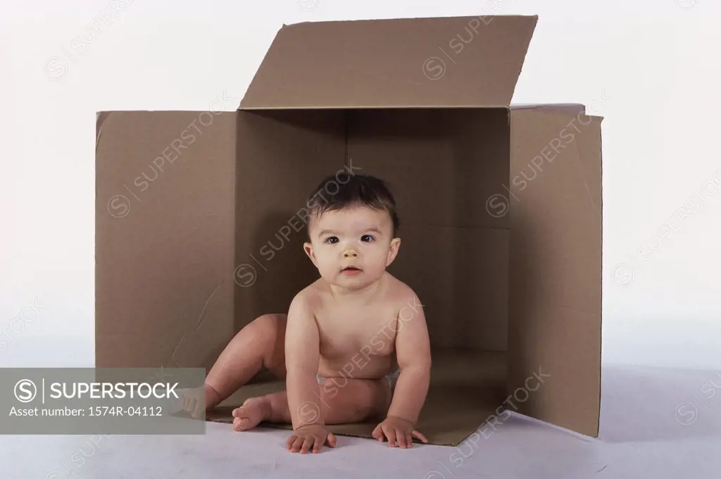 Baby boy sitting in an empty cardboard box