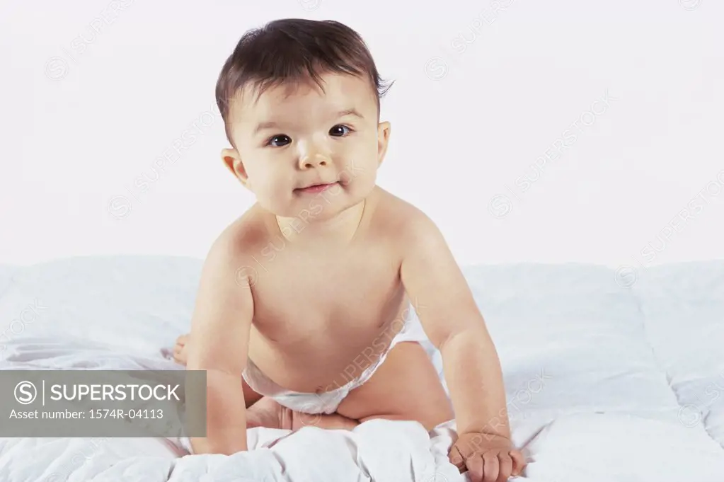 Portrait of a baby boy sitting on a bed