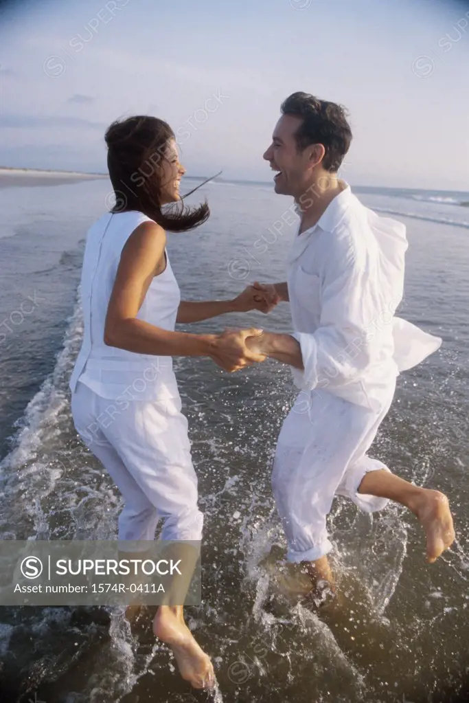 Side profile of a young couple playing on the beach