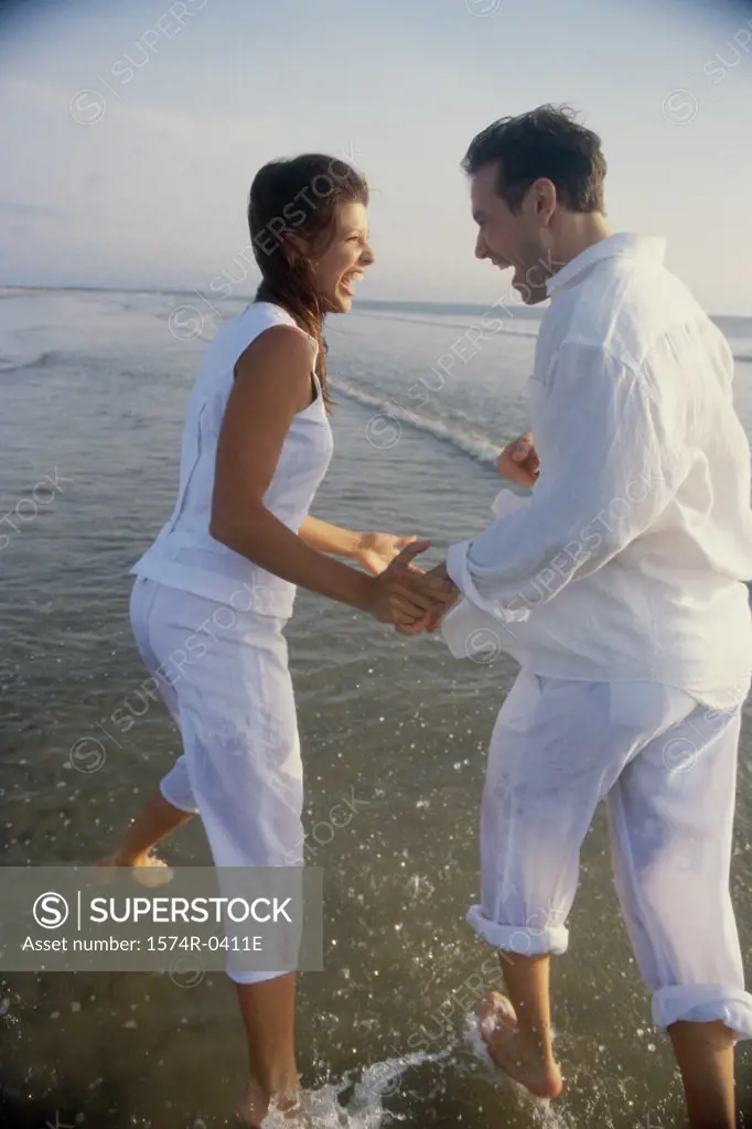 Side profile of a young couple playing on the beach
