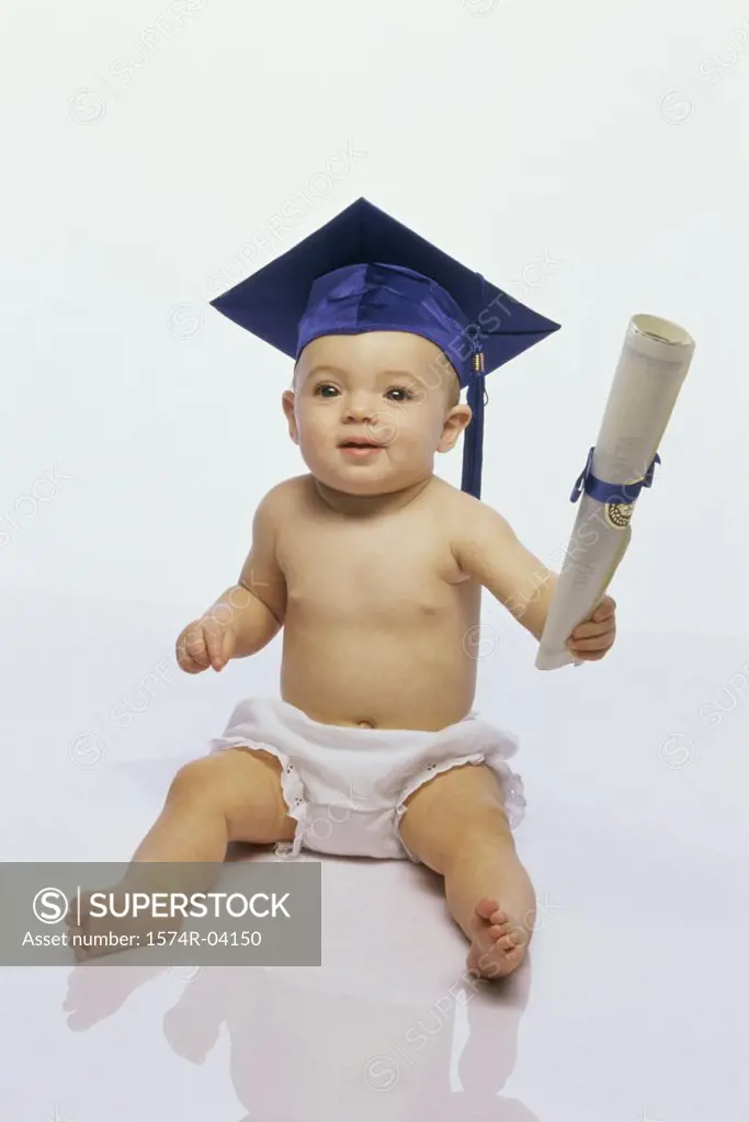 Baby boy wearing a mortar board holding a diploma