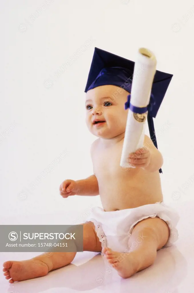 Baby boy wearing a mortar board holding a diploma