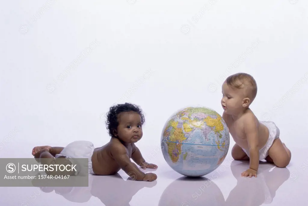Baby boy and a baby girl playing with a globe