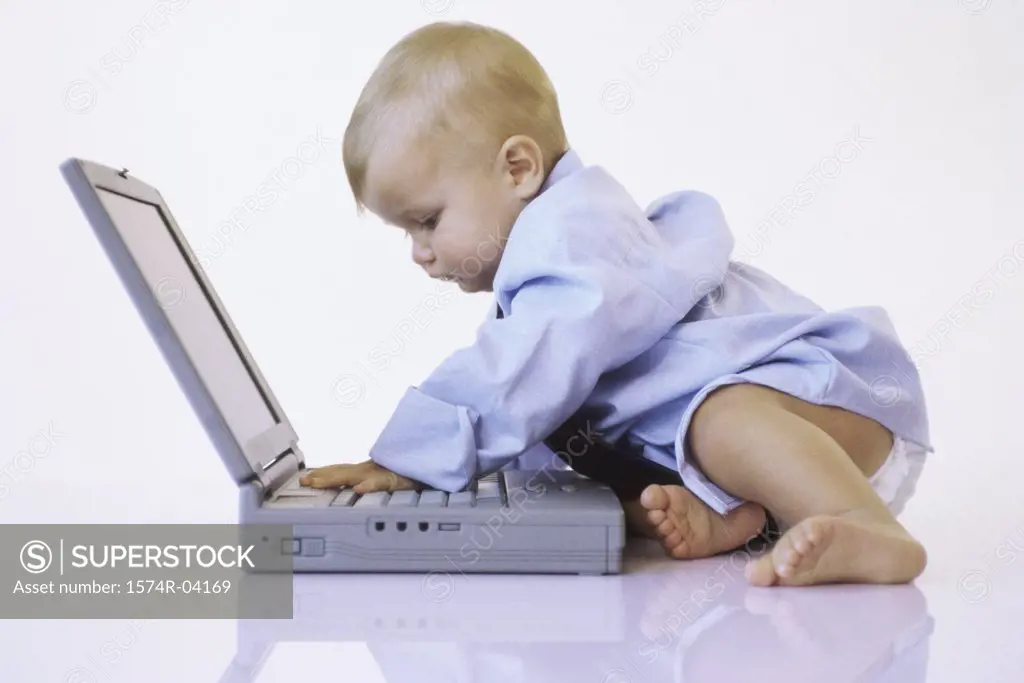 Side profile of a baby boy touching a laptop