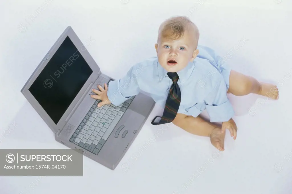 Portrait of a baby boy touching a laptop