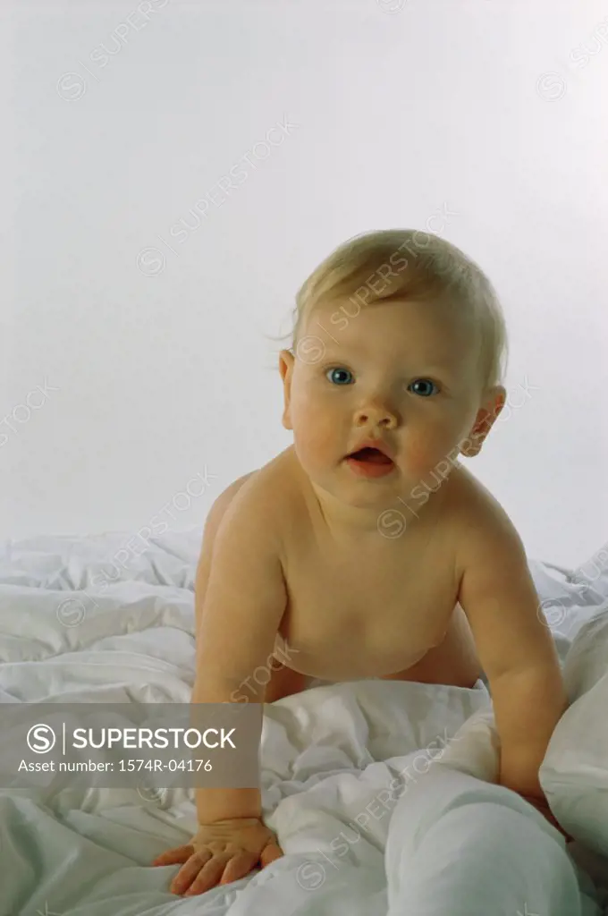 Portrait of a baby boy crawling on a bed