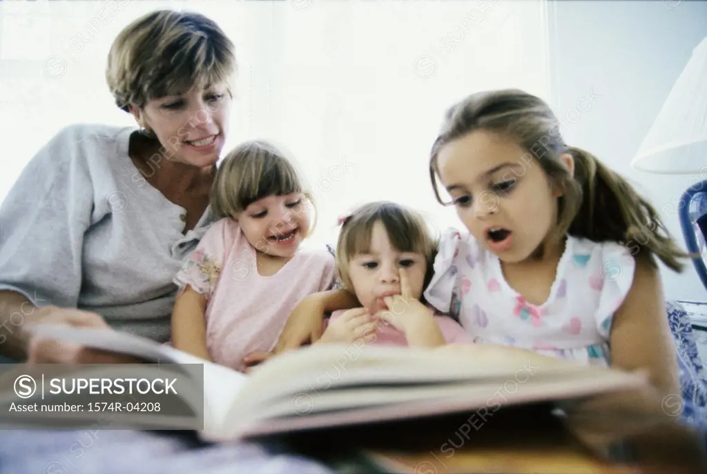 Mother reading a book with her three daughters