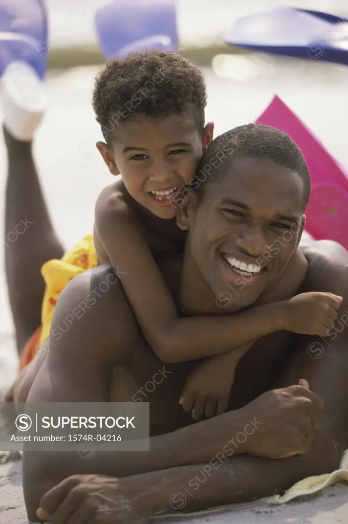 Portrait of a father lying with his son on the beach