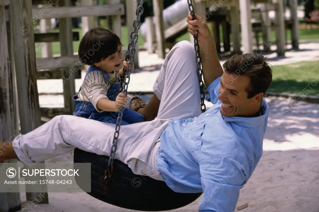 Side profile of a father and his son playing on a tire swing