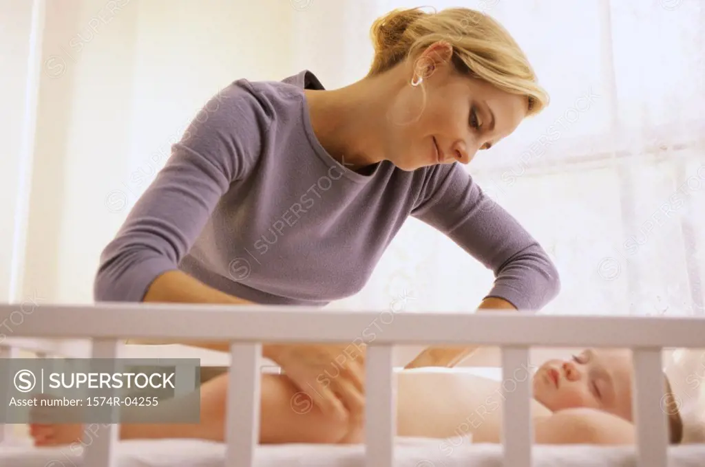 Mother adjusting sleeping her baby's diaper