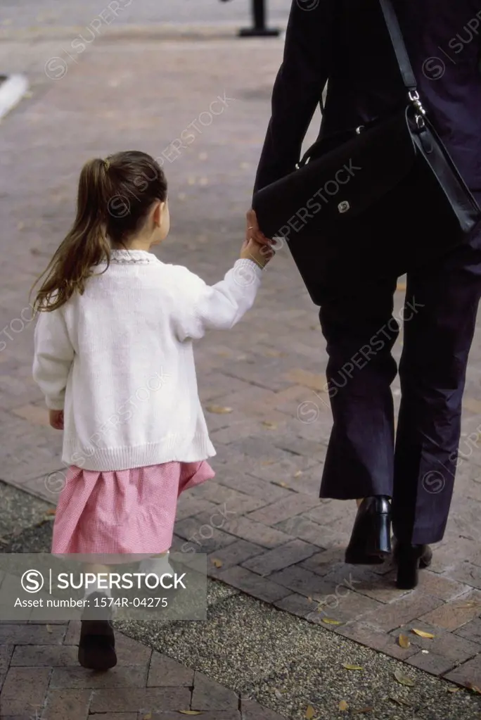Rear view of a mother holding hands while walking with her daughter