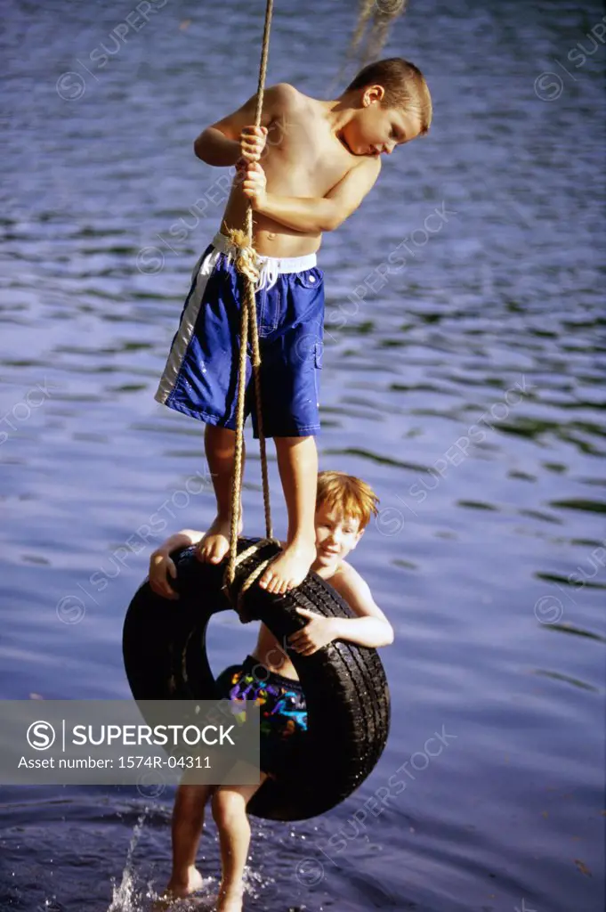 Two boys playing on a tire swing