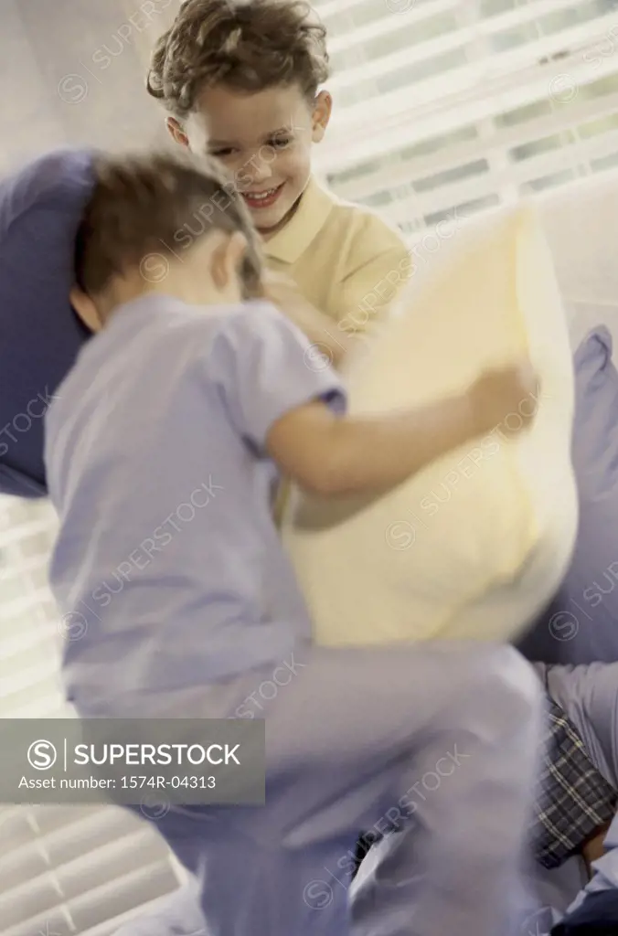 Two boys having a pillow fight on a bed