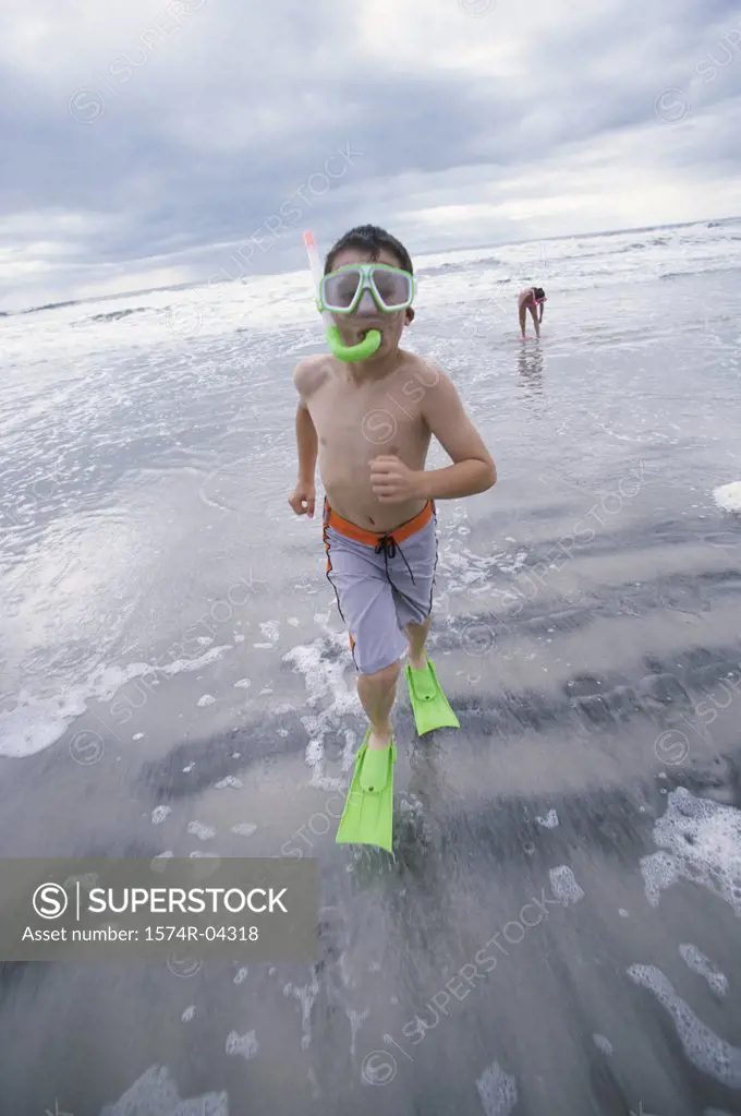 Portrait of a boy wearing a snorkel running on the beach