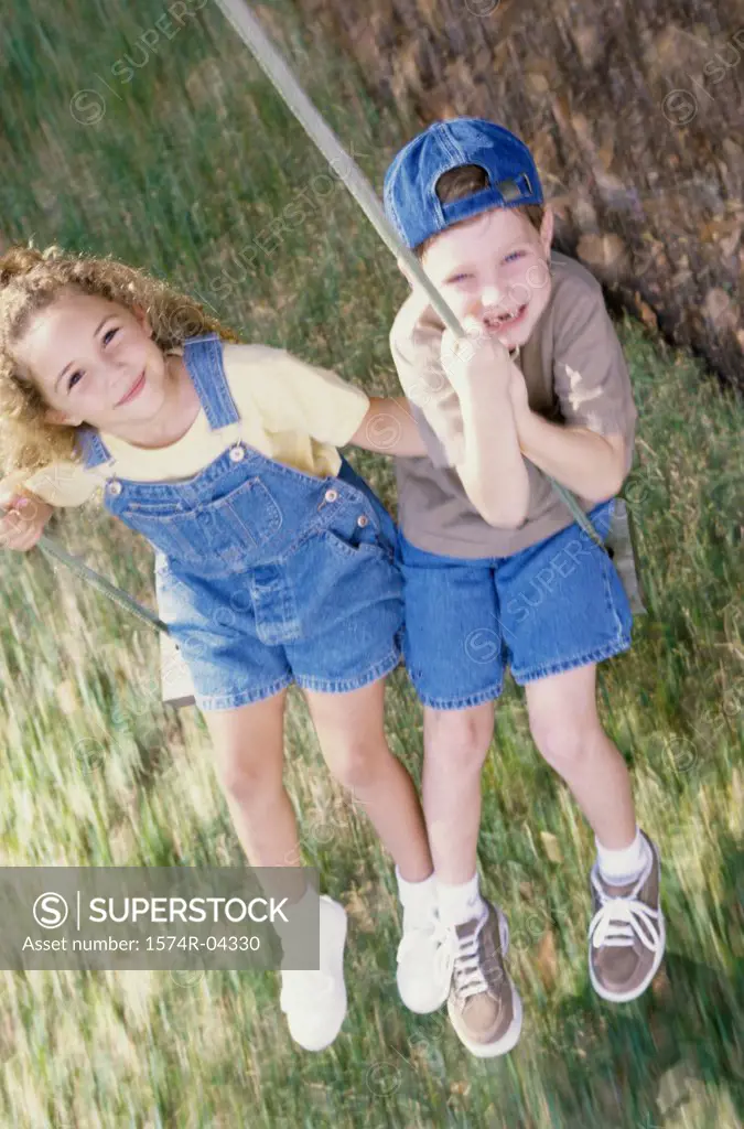 Portrait of a girl and a boy sitting on a swing