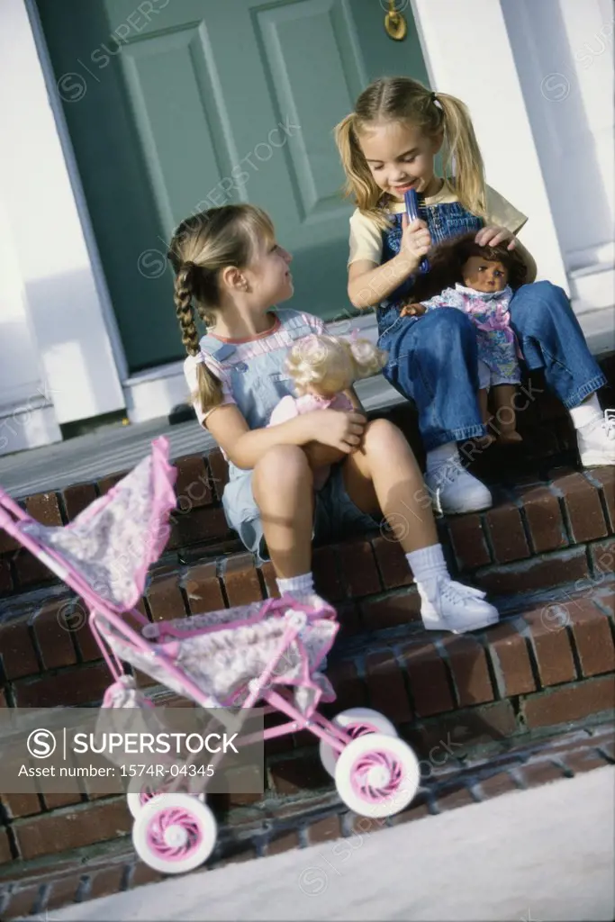 Two girls sitting together with their dolls