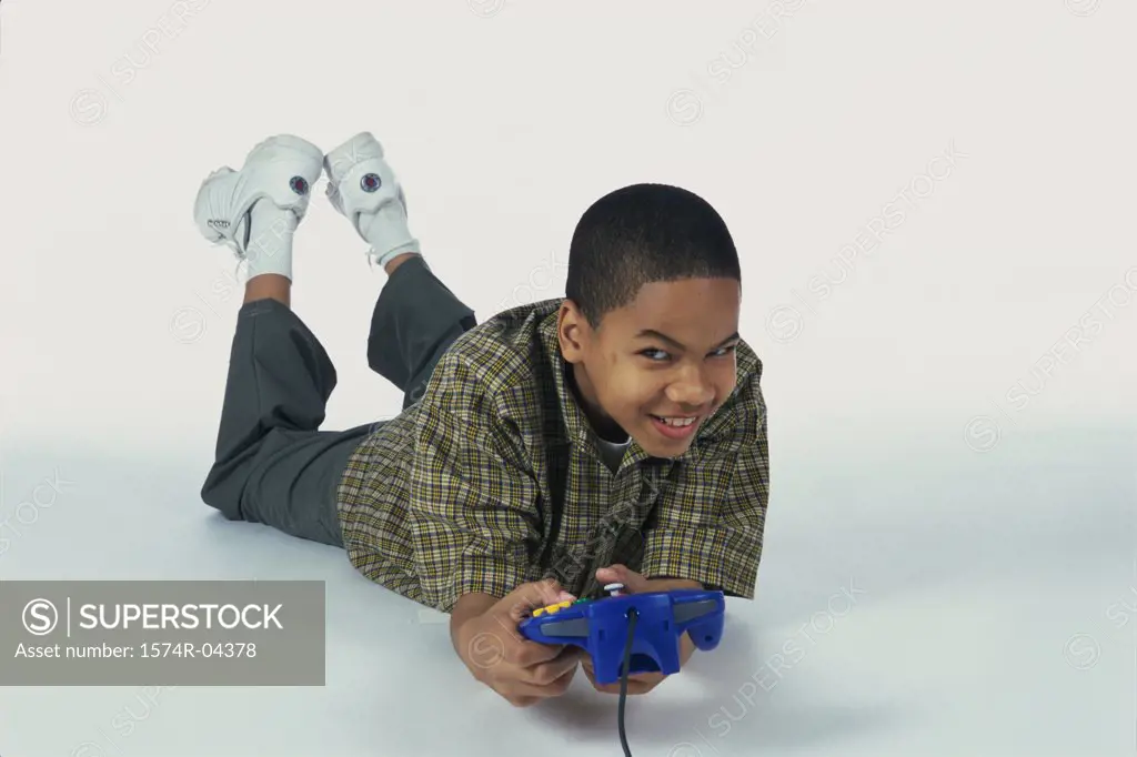 Portrait of a boy lying on the floor holding a game joystick