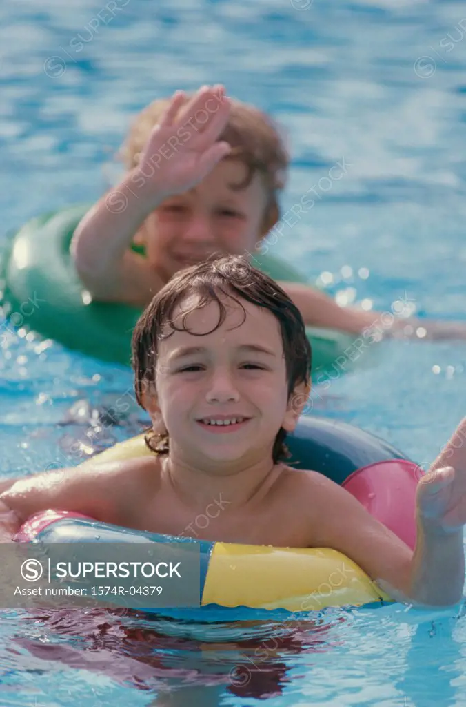 Two boys wearing inner tubes in a swimming pool