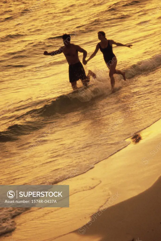 Silhouette of a young couple running on the beach