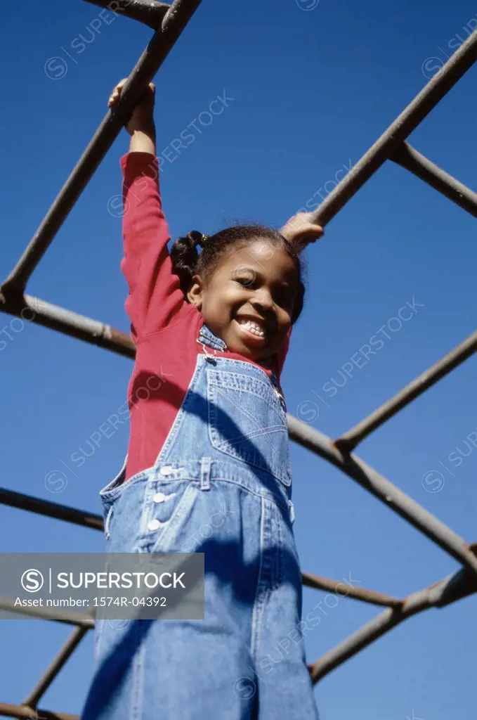 Low angle view of a girl hanging on monkey bars