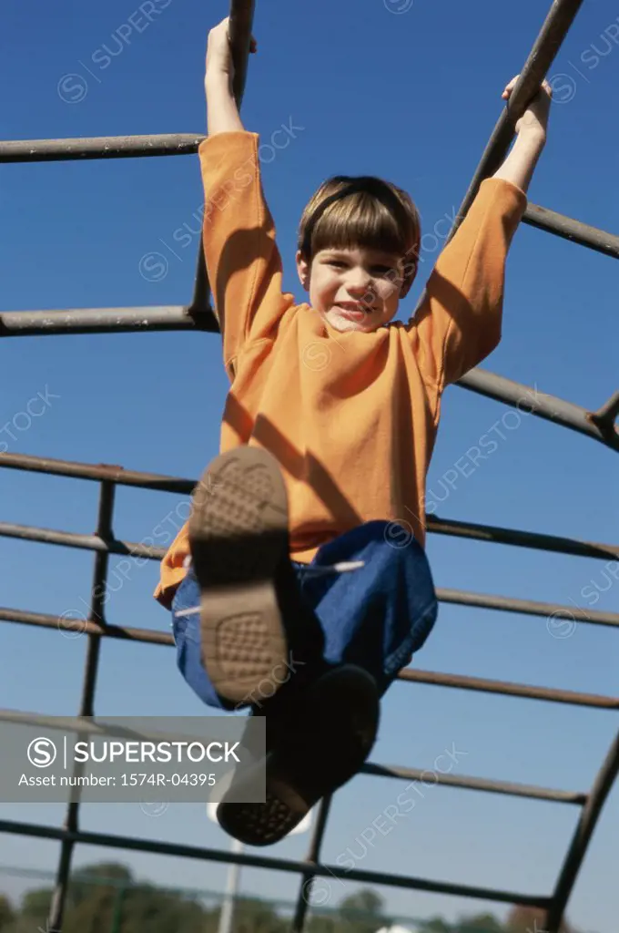 Low angle view of a boy hanging from monkey bars