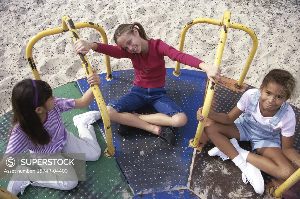 High angle view of three girls playing on a merry-go-round