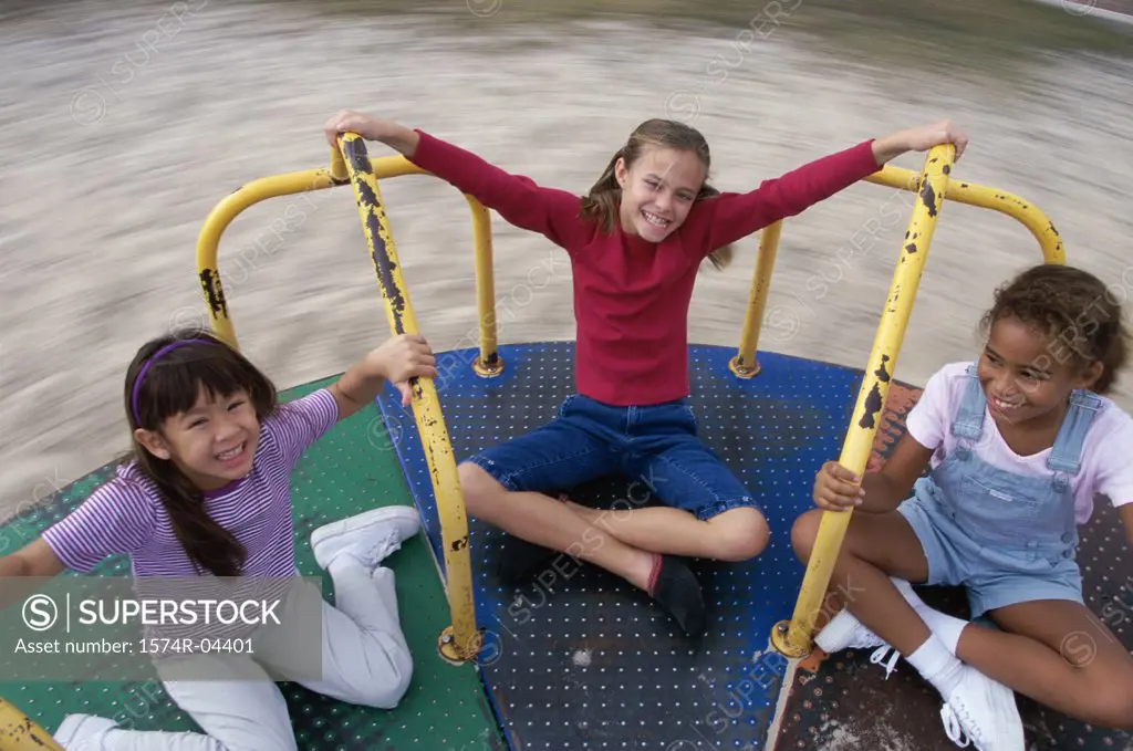 High angle view of three girls playing on a merry-go-round