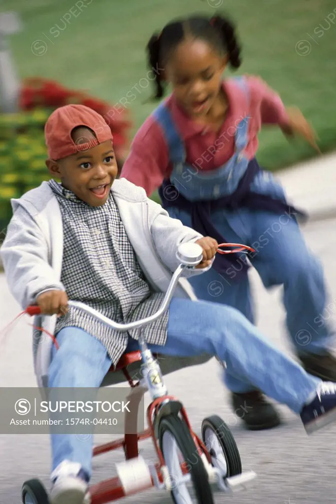 Boy and a girl playing on a tricycle
