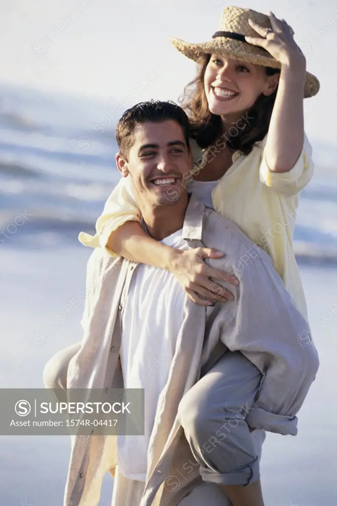 Young woman riding piggyback on a young man on the beach