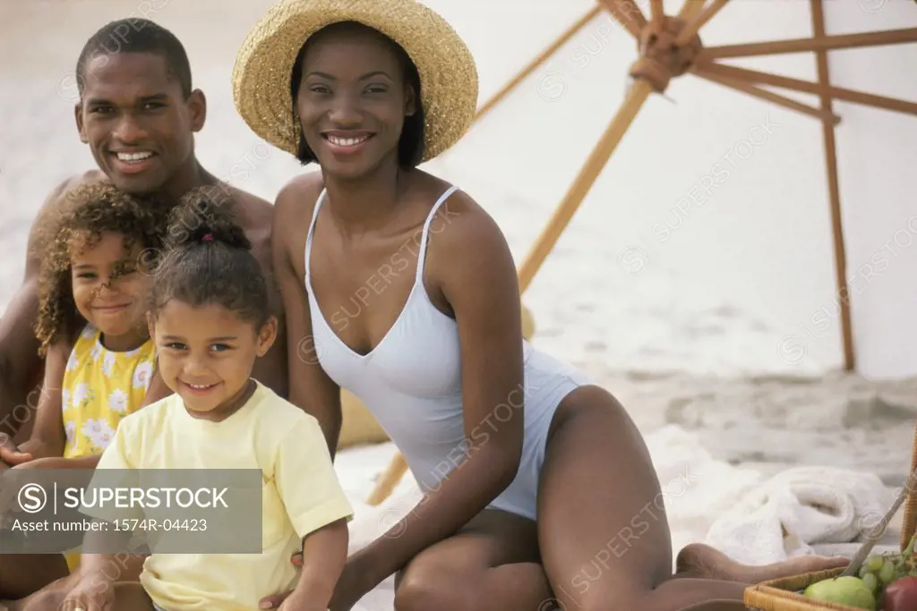 Portrait of parents with their two daughters sitting on the beach