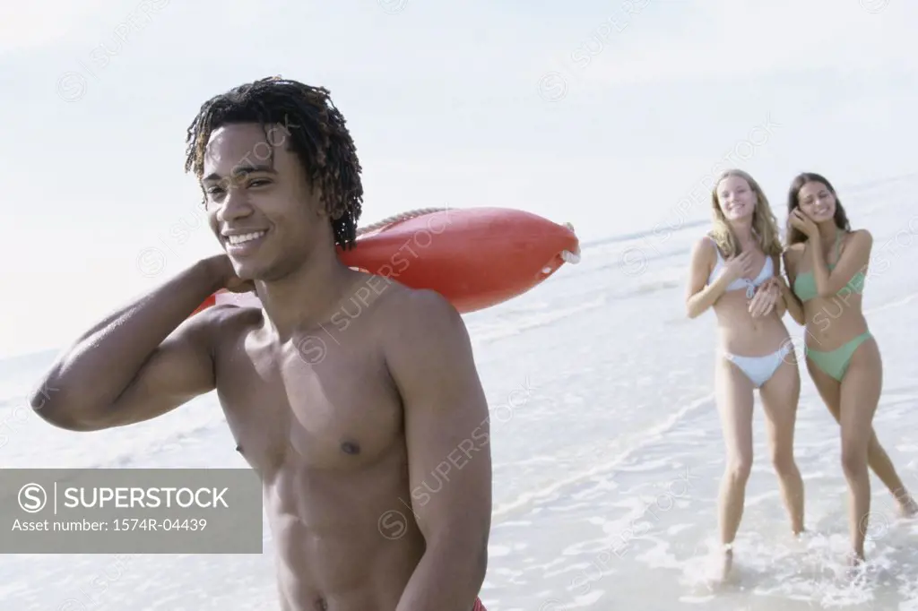 Teenage boy on the beach with two teenage girls behind him