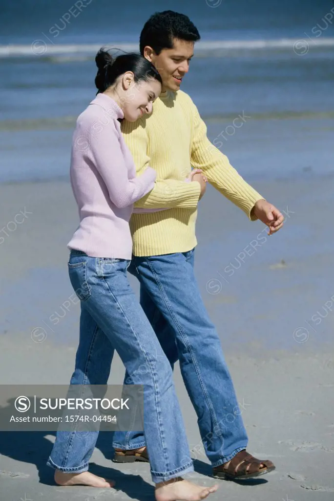 Young couple walking on the beach holding hands