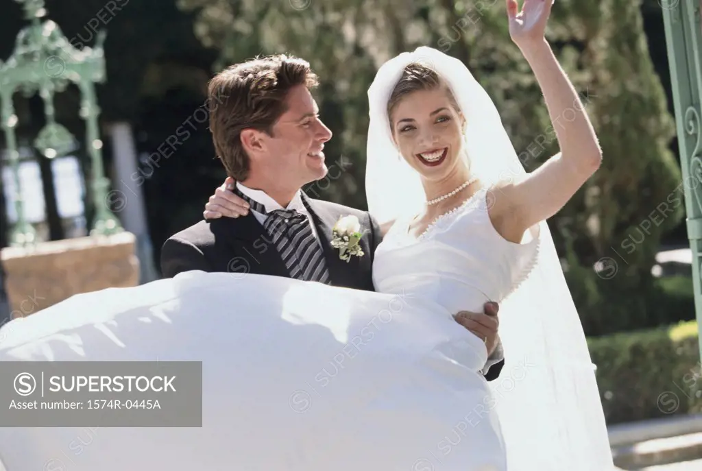 Young man carrying a young woman at their wedding